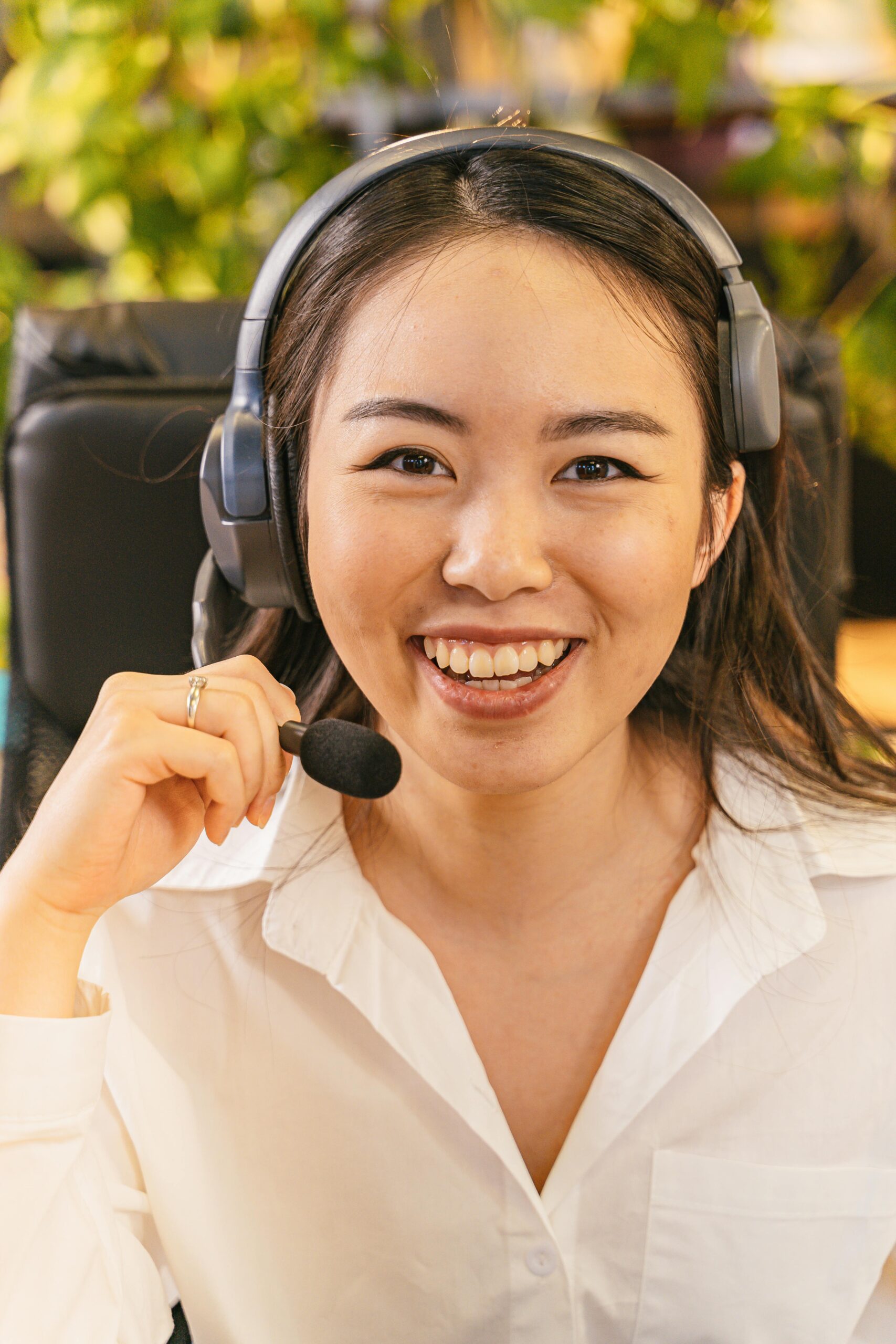 A young woman in an office setting wearing a headset, ready to assist over the phone.